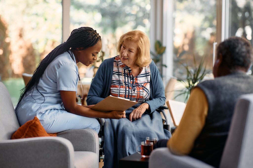 Happy senior woman going through her medical data with young nurse at residential care home.