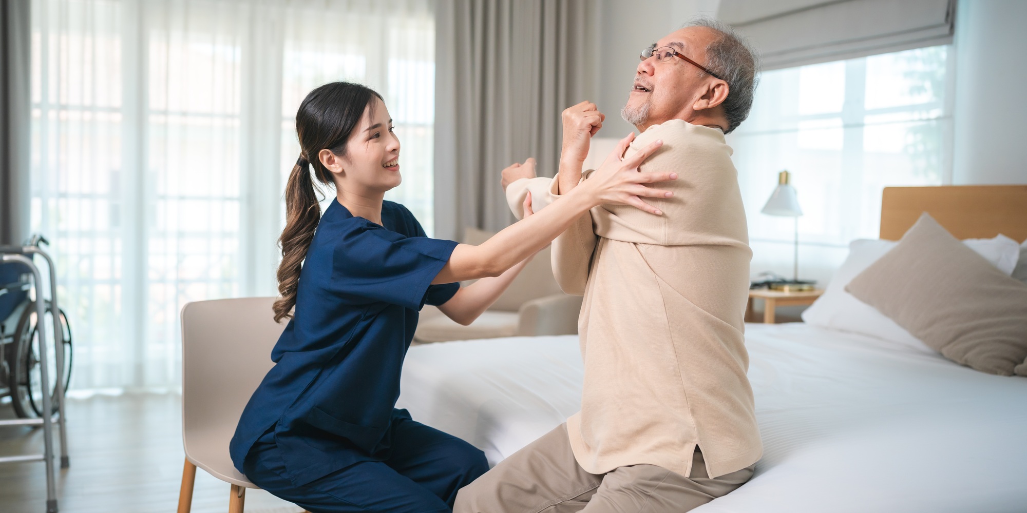 Young asian female nurse care giver helping asian senior old man in living area of nursing home