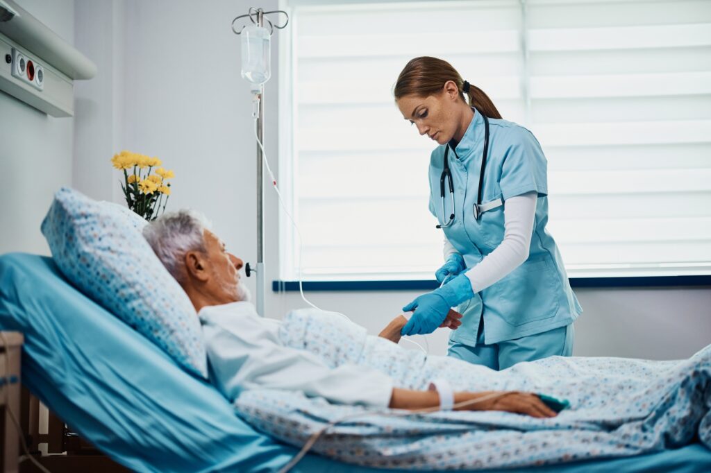 Mid adult nurse checking IV drip of senior patient at hospital ward.